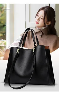 Detail der schwarzen Handtasche mit Litschi-Lederstruktur und goldenen Beschlägen