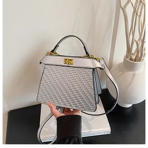 Detailed view of woven texture and golden twist lock on silver metallic satchel bag
