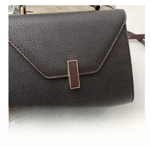 Close-up of deep brown pebbled leather handbag with rectangular metal clasp and flap