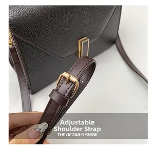 Detail of adjustable leather strap with gold metal buckle on a brown tote bag