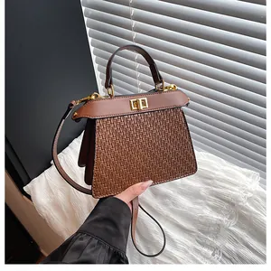 Detail of a brown woven texture handbag with golden twist lock and leather handle