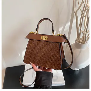 Detail of vintage brown woven leather handbag featuring a gold twist lock and top handle