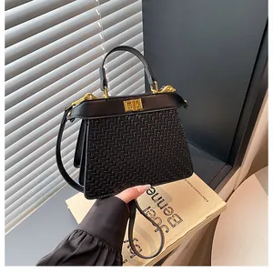 Detailed view of woven black leather handbag with golden metal hardware and twist lock closure