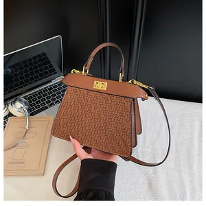Detailed view of brown woven texture handbag with golden twist-lock and metal hardware