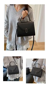 Detail of black pebbled leather tote with V-shaped flap and gold metal lock hardware