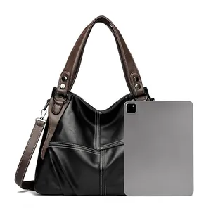 Close-up of black pebble leather tote with brown straps and tablet for size reference