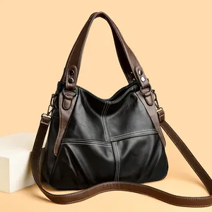 Detail of black crossbody bag with brown accents and white contrast double stitching