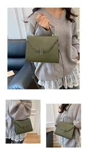 Detail of dark green pebble leather tote bag with gold lock and thin shoulder strap