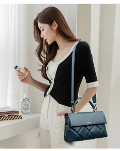Detailed view of dark blue quilted leather handbag with gold metal clasp and logo