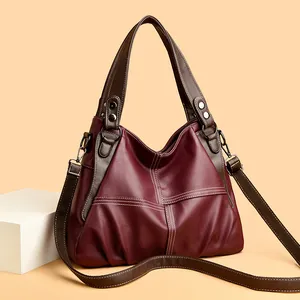 Detail view of burgundy lychee-grain faux leather bag with contrast stitching and pleats