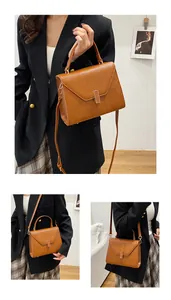 Detail of caramel pebbled leather tote with gold metal buckle and top handle grip
