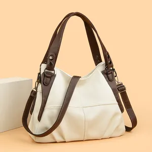 Detailed stitching on beige and brown leather tote with antique bronze hardware