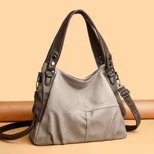 Macro shot of hobo bag featuring contrasting leather textures and vintage metal rivets