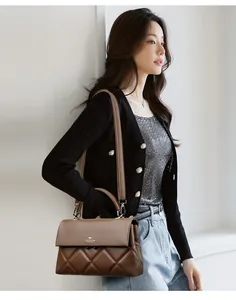 Detail of brown quilted leather bag with metallic logo and detachable shoulder strap