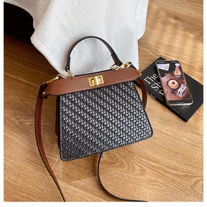 Top view of two-tone woven leather trapezoid handbag with gold metal twist lock detail