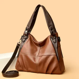 Detail of the brown leather tote featuring decorative white stitching and metal hardware