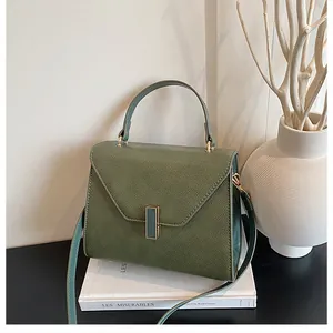 Close-up of dark green textured leather tote bag with elegant gold metal clasp on books