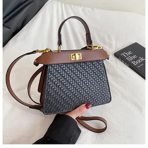 Detail of black woven texture and brown leather handle with gold twist lock