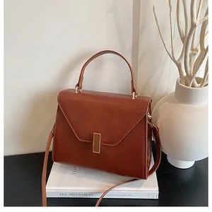 Detailed view of a brown pebbled leather tote bag with gold metal lock on a book