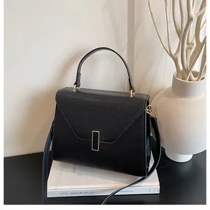 Detail of black pebbled leather tote bag with elegant gold buckle and structured top handle