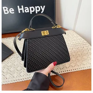 Detail shot of black woven handbag featuring a gold twist lock and a smooth leather flap