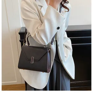 Detail of a dark textured leather handbag with a metal buckle lock and a rounded top handle