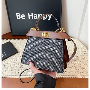 Detail of black woven handbag featuring brown leather handle and gold twist lock closure
