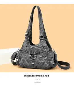 Détail du sac en cuir matelassé gris foncé avec fermetures éclair fleur et bandoulière