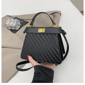 Detail of black woven texture handbag with golden twist lock and leather handle