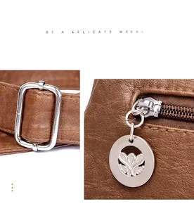 Macro detail of the pebbled brown PU leather, silver buckle, and floral zipper puller