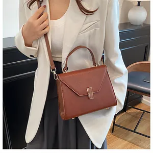 Detail of a brown lychee pattern handbag featuring a gold buckle and shoulder strap