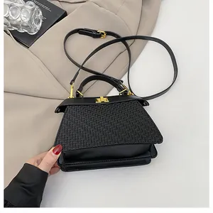 Close-up of black crossbody bag featuring woven texture flap and golden twist lock detail