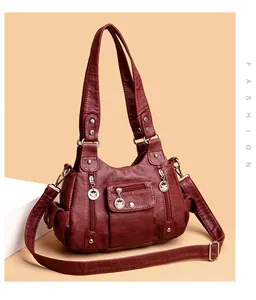 Detail view of burgundy multi-pocket handbag with silver zippers and bird charm