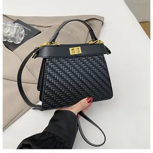 Close-up of black woven leather handbag featuring a golden swivel lock and refined texture