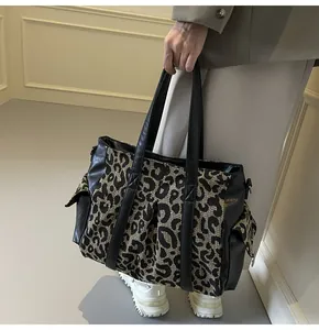 Detail of leopard print canvas tote bag featuring black leather pockets and wide shoulder strap