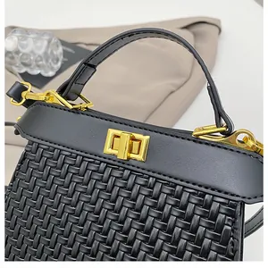 Detail of woven texture and golden rectangle buckle on black leather handbag