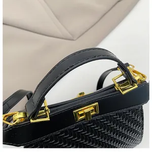 Detail of woven texture craftsmanship with golden metallic clasp on black handbag