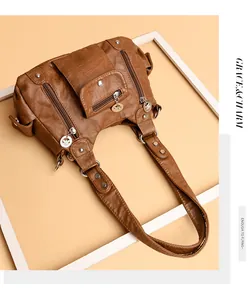 Close-up of vintage brown multi-pocket faux leather bag with metal rivets and zipper detail