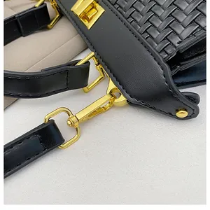 Close-up of black woven leather handbag showing gold metal clasp and premium texture