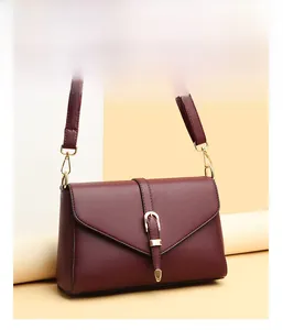 Detail of wine red crossbody bag showing matte texture and gold buckle decoration
