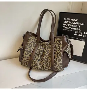 Detailed side view of leopard print canvas tote bag with brown leather trim and side pocket