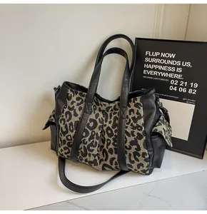 Close-up of leopard print canvas tote bag featuring black leather straps and side pockets