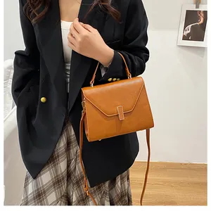 Detail of brown litchi pattern leather tote with gold buckle and top handle on a model