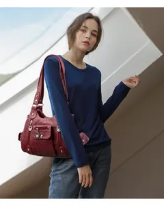 Detail view of burgundy washed soft PU leather multi-pocket shoulder bag on a model