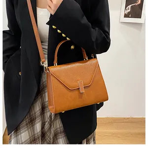 Brown textured leather handbag styled with a black blazer and skirt for a commute look
