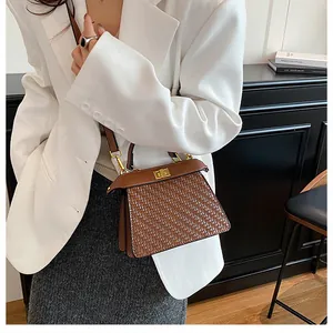 Detail of dark brown woven texture shoulder bag with golden rectangular turn-lock