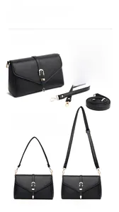 Detail of black leather crossbody bag featuring dual straps and gold metal hook buckles