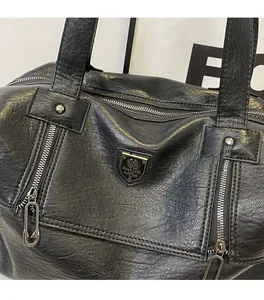 Close-up of black retro tote bag featuring soft leather texture and metal zipper details