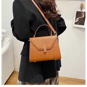 Brown textured PU leather tote bag with V-cut flap and metal buckle on professional model