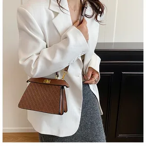 Detail of a brown woven texture shoulder bag with golden twist lock on a white blazer